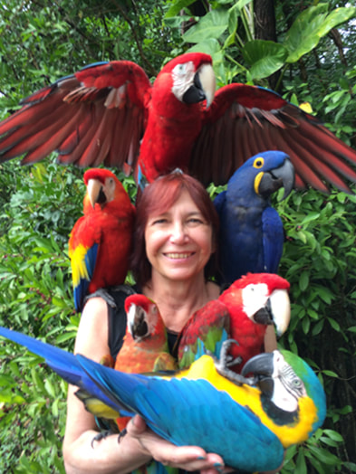 Photo of Realtor Salesperson, Dianne Moore of Savio Realty Ltd. Puna Office, holding a colorful group of parrots